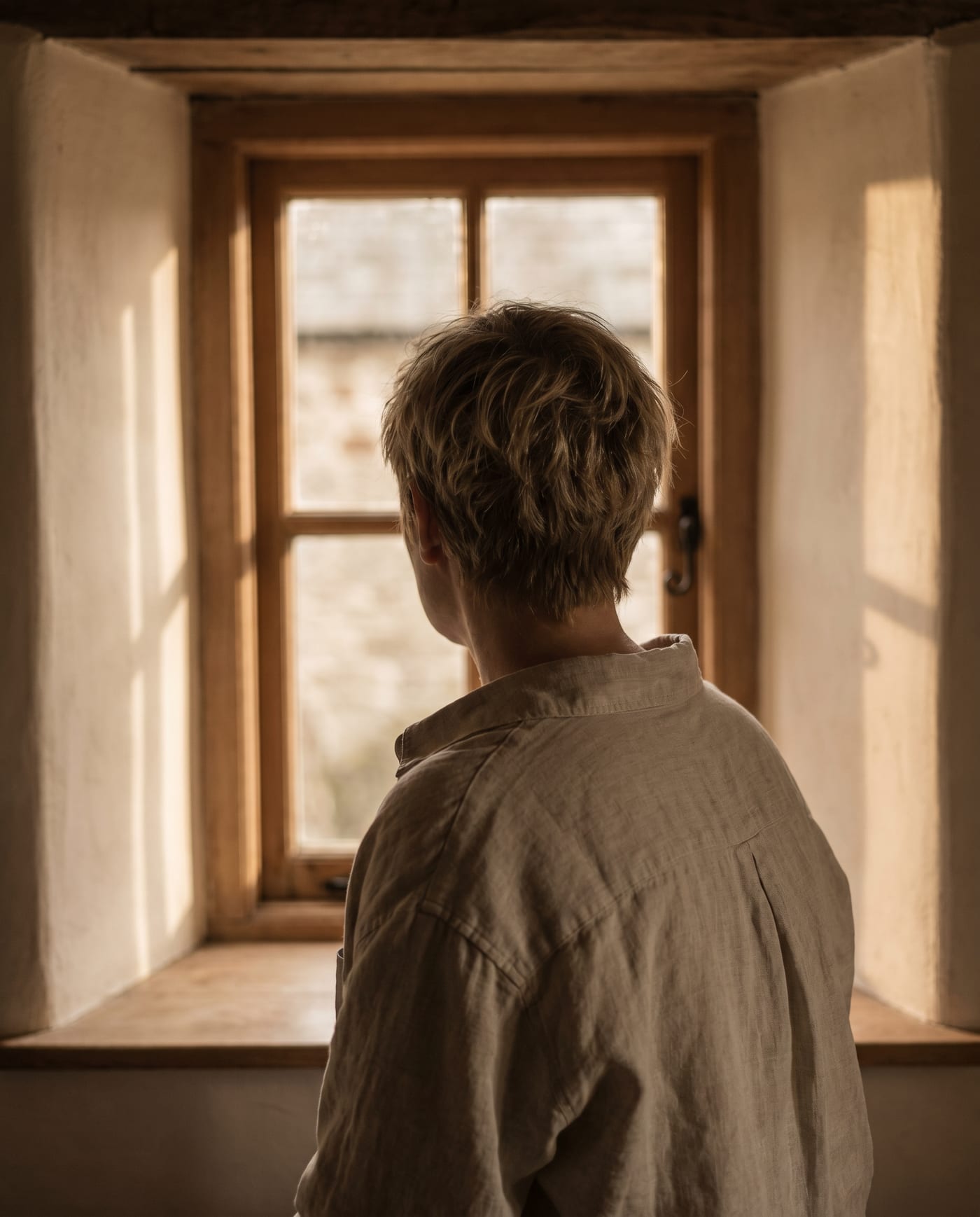 Nuca y hombro de un adulto ante la ventana de la mañana.